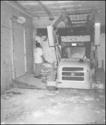A skid loader working inside the gutted warehouse